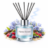 Diffuser with 'Alpine Escape' label surrounded by flowers and berries on a white background