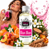 A bottle of Fizzy Whiz Bon Bon fragrance oil centered on a white background, surrounded by illustrated scent ingredients including oranges, peaches, cinnamon, wood chips, white flowers, and pink liquid splashes. A woman appears in the upper left holding a pink perfume bottle, suggesting a fragrance product.