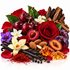 A styled botanical and botanical blend arrangement featuring dark red cherries, a large red rose, red and white flowers, vanilla beans, almonds, cinnamon sticks, amber-colored resin cubes, and small purple blossoms on a white background.