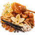 A styled arrangement of honey and vanilla ingredients on a white background, including a honeycomb dipper, dripping honey, honey cubes, vanilla beans, vanilla extract swirl, vanilla crystals, dried flowers, and vanilla pods.