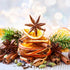 A Christmas spice fragrance oil product displayed with holiday-themed decorations, including dried orange slices, cinnamon sticks, and pine needles.
