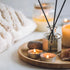 A bottle of comforting therapy fragrance oil with a concentration of 100% pure scent, displayed alongside lit candles and a towel, suggesting its use in a relaxing spa setting.