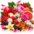 A vibrant still life arrangement of colorful ingredients, including a red apple, pink peony and rose, red grapes, raspberries, vanilla beans, amber honey, cinnamon sticks, and white blossoms, set against a clean white background.