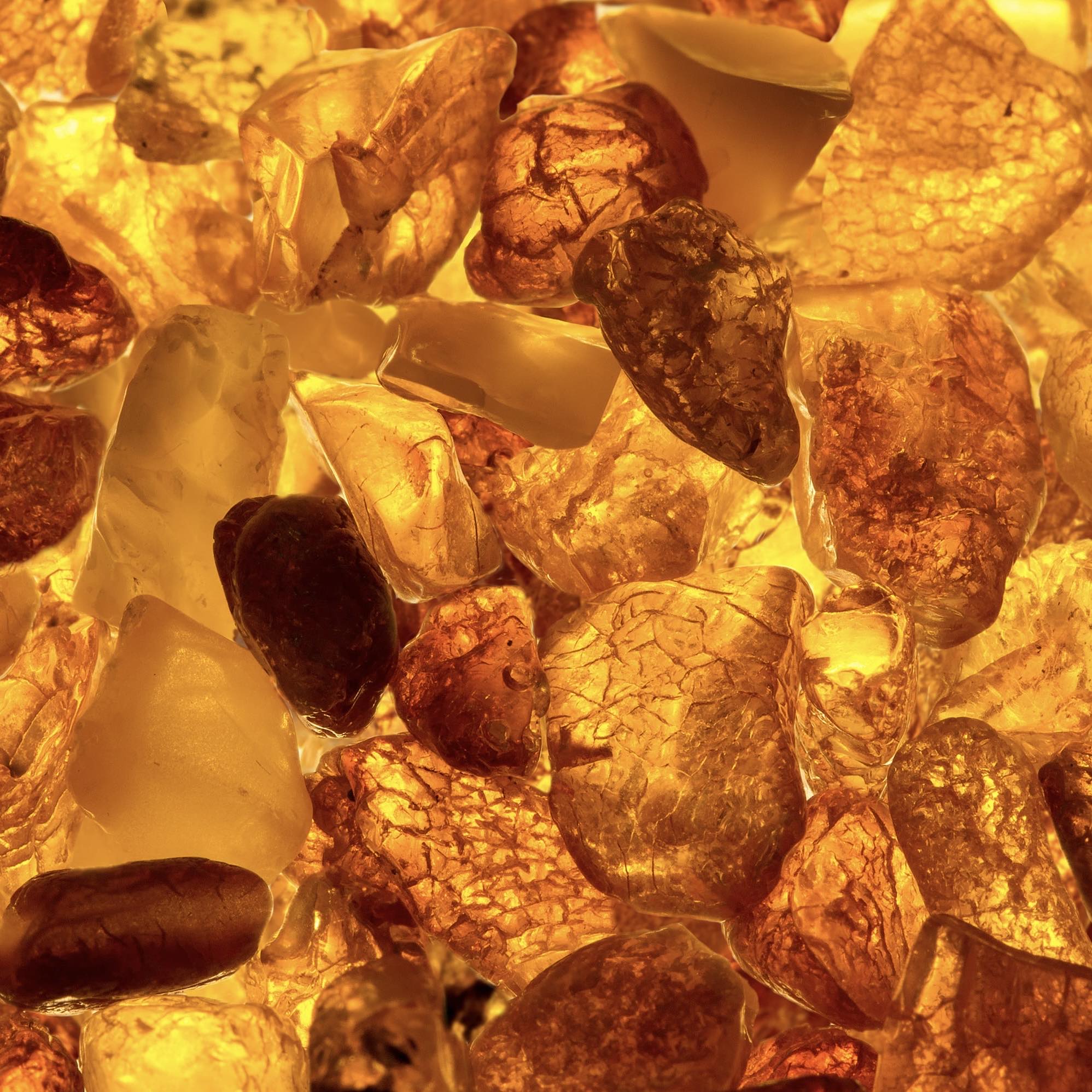 A close-up image of amber-colored fragrance oil with apparent suspended particles, reflecting light and creating a visually rich, textured appearance.