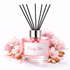 Pink diffuser bottle labeled 'Fizzy Star' with black reeds surrounded by pink flowers and almonds on a white background