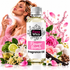 A bottle of Fizzy Whiz Flower Bomb fragrance oil centered in front of a woman spraying perfume, surrounded by pink roses, limes, vanilla beans, flowers, and a pink flower-splash graphic on a white background.