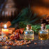 Two small glass bottles with cork stoppers, filled with yellow liquid, presented next to a lit candle and natural elements on a dark background.