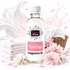 A bottle of Bizzy Whiz Fresh Caps Fragrance Oil centered on a white background, surrounded by folded white towels, pink flowers, petals, and a wicker basket with white fabric.