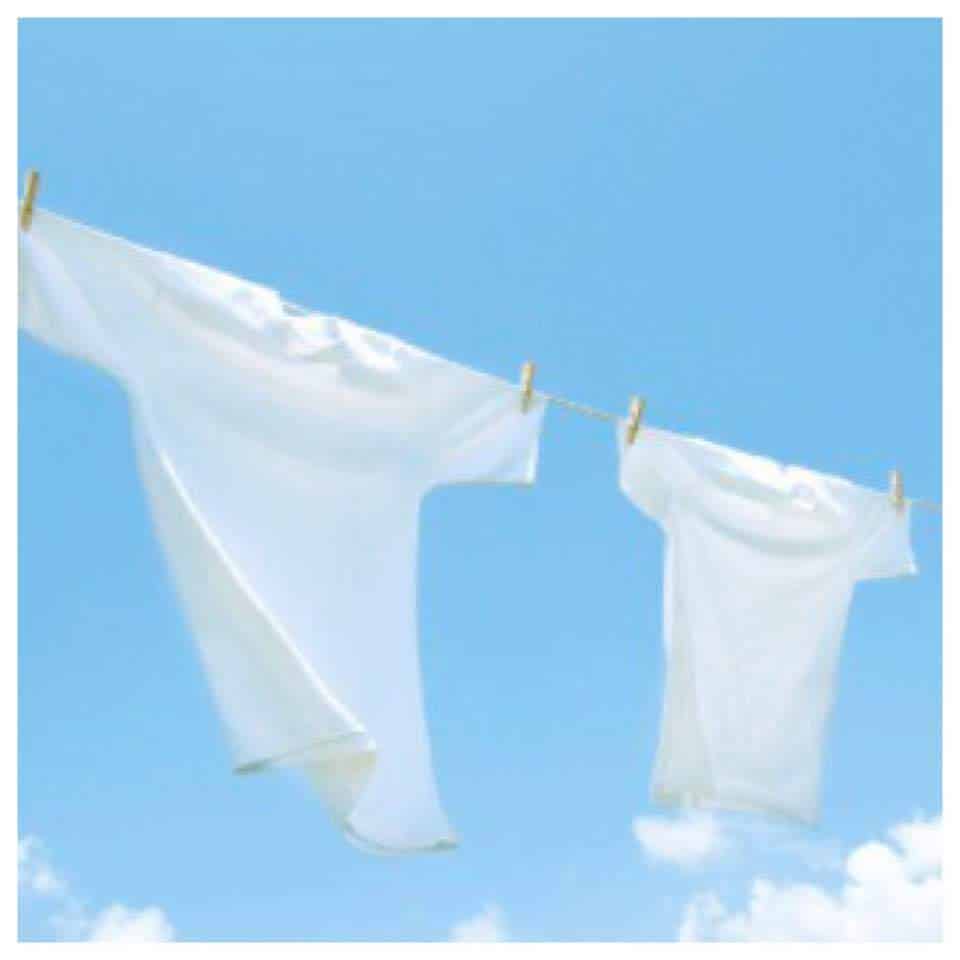 Two white t-shirts hanging on a clothesline against a blue sky with clouds.