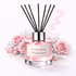 Clear reed diffuser bottle surrounding roses on a white background 