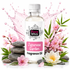 A bottle of Fizzy Whiz Japanese Garden Fragrance Oil centered on a white background, surrounded by pink cherry blossoms, green leaves, stacked gray stones, and a pink liquid splash behind it.
