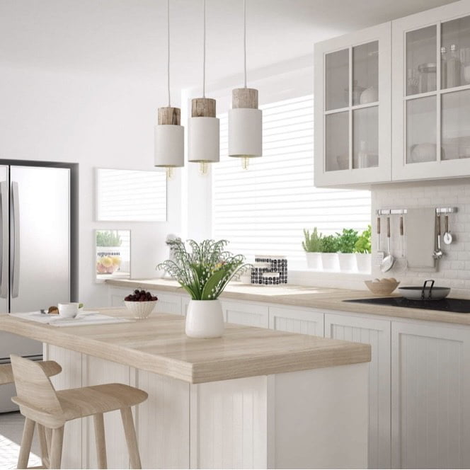 A bright and airy kitchen with a white color scheme, featuring a kitchen island, hanging pendant lights, and various kitchen appliances. A bottle of fragrance oil is not visible in this image.