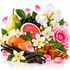 A colorful still life arrangement of food and flowers on a white background, including a pear, grapefruit half, orange segments, blackberries, vanilla beans, caramel cubes, cinnamon sticks, pink and white flowers, and green leaves.