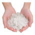 Two hands holding a pile of white sea salt crystals on a white background