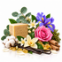 A rectangular bar of Savon de Marseille soap styled with botanical ingredients including a pink rose, purple iris, white vanillas, cotton boll, eucalyptus leaves, cinnamon sticks, and amber crystals on a white background.