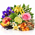 A colorful botanical and botanical blend arrangement featuring purple irises, a pink rose, yellow mace, vanilla beans, a lime slice, white lily of the valley, peach slices, amber crystals, cinnamon sticks, and green leaves on a white reflective background.