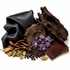 A styled flat-lay of natural materials on a white background, featuring a piece of textured black leather, a smaller piece of brown leather, a dark wood slice, dried bark, green cardamom pods, black peppercorns, and purple flowers.