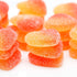 A close-up image of orange sherbet candy pieces, with a focus on their vibrant orange and red colors and textured sugar coating.