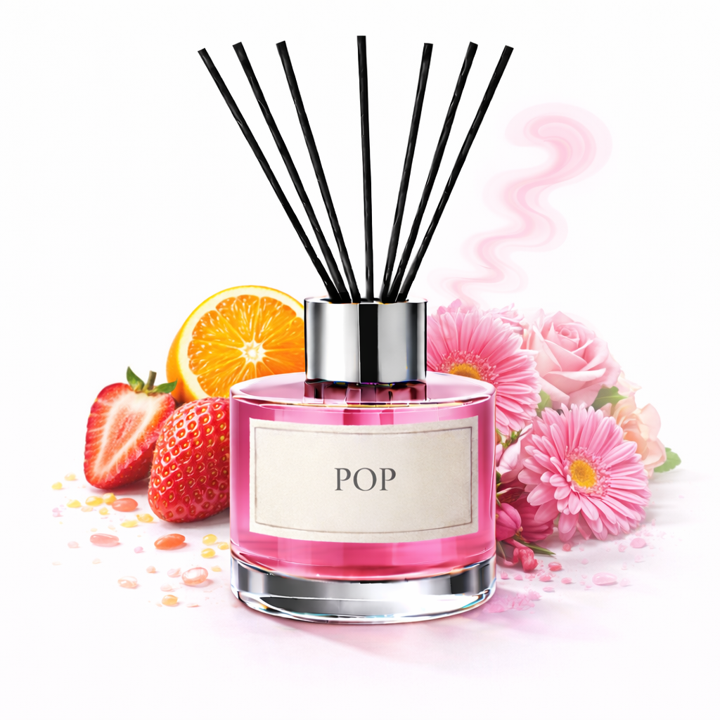 Pink diffuser with black sticks, surrounded by fruits and flowers on a white background