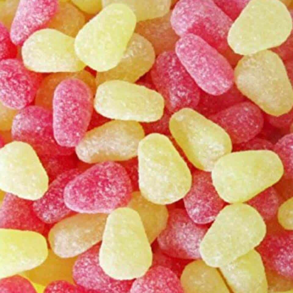 A close-up image of small, candy-like pellets in yellow and red, resembling a fruity sweets or gummy candies.