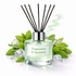 Reed diffuser with peppermint and spearmint fragrance surrounded by green leaves and flowers on a white background