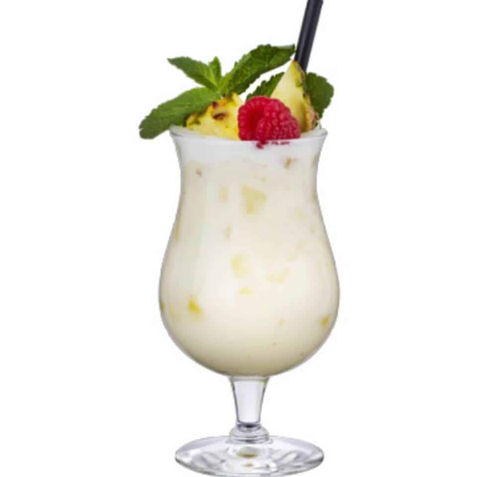 A glass of pina colada fragrance oil garnished with a pineapple slice and a cherry