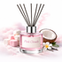 Diffuser with 'Pink Clouds' label surrounded by coconut halves, flowers, and marshmallows on a soft pink background