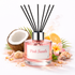 Reed diffuser labeled 'Pink Sands' with coconut, lemon, and flowers on a white background