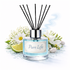 Diffuser with 'Pure Life' label surrounded by flowers and a lime wedge on a white background