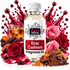A bottle of Fizzy Whiz Rose Cashmere fragrance oil centered on a white background, surrounded by roses, liquid splashes, a glass of amber liquid, spices, and chocolate pieces. The product label reads 'Fizzy Whiz' and 'Rose Cashmere Fragrance Oil'.