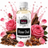 A bottle of Fizzy Whiz Rose Oud Fragrance Oil centered on a white background, surrounded by pink roses, rose petals, wood chips, and amber crystals with pink liquid splashes behind it.