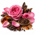 A styled botanical arrangement on a white background featuring a large pink rose, smaller pink rosebud, pink petals, dark brown wood pieces, amber-colored crystals, star anise, and a small bowl of dark brown seeds or spices.