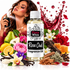 A bottle of Fizzy Whiz Rose Oud Fragrance Oil centered on a white background, surrounded by rose petals, a woman spraying perfume, and various floral and botanical ingredients including roses, pears, lemons, vanilla beans, cinnamon, and honeycomb. A metallic red perfume spray splash graphic appears behind the bottle.