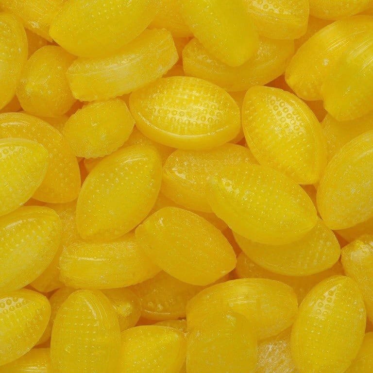 A close-up image of yellow, oval-shaped sherbet lemon candies.