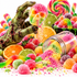 A Halloween-themed candy display featuring a green zombie hand holding a pink and green sugar skull candy, with colorful gummy candies, gummy worms, sliced oranges, limes, and a spilled jar of multicolored sprinkles on a white background.