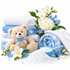 A styled product arrangement on a white background featuring folded and rolled white and light blue towels, a beige teddy bear with a blue bow, white and blue flowers, a blue scoop, and a pile of white bath or body beads with light blue specks.