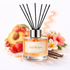 Reed diffuser with 'Sol Beijos' label surrounded by fruits, flowers, and vanilla beans on a white background