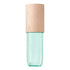 A cosmetic spray bottle with a translucent mint green glass body and a light natural wood cap, shown against a plain white background.