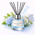 Diffuser with 'Spring Awakening Plus' label surrounded by flowers and towels on a white background