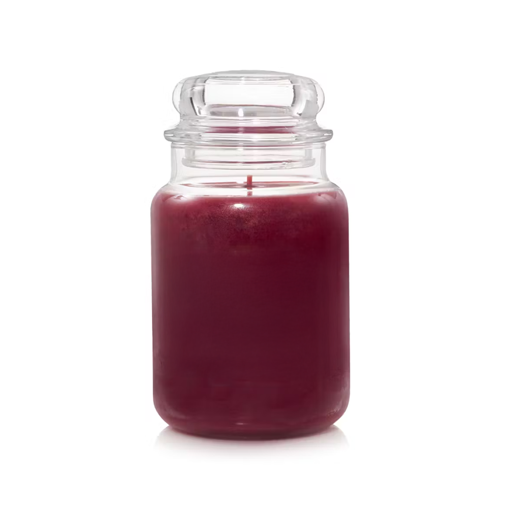 A jar of Sugar Plum fragrance oil, with a red tinted liquid, placed in a clear glass jar.