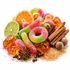 A colorful assortment of candy and spices arranged on a white background, including pink and green sour gummy worms, orange and lime slices, cinnamon sticks, star anise, cloves, brown sugar, and translucent amber sugar cubes.