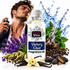 A bottle of Fizzy Whiz Victory Elixir Fragrance Oil centered in a promotional composition, surrounded by fragrance ingredients including lavender, vanilla beans, cardamom pods, cinnamon, and mint leaves. A man is partially visible on the left spraying fragrance, with blue water splash graphics in the background.