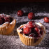 A photo depicting two small tartlet tins with a cherry and ginger frosting topping, dusted with powdered sugar, designed to represent a fragrance oil product.