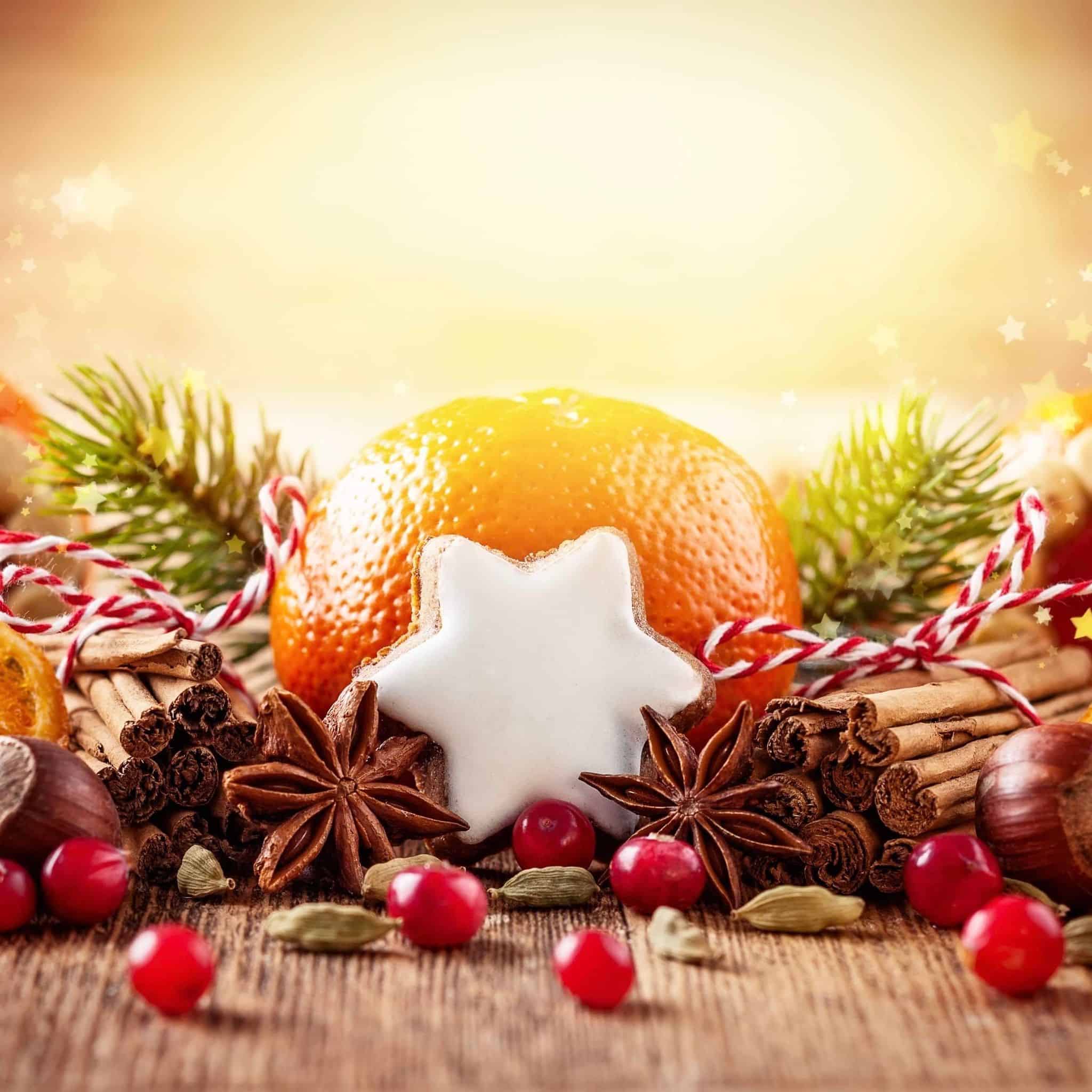 A festive arrangement featuring winter spices such as cinnamon sticks, nutmeg, and aniseed with an orange and pine needles. A white star-shaped cookie cutter is also included, suggesting the use of the oil in baking.