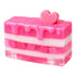 Pink layered cake-shaped soap with a heart on top against a white background
