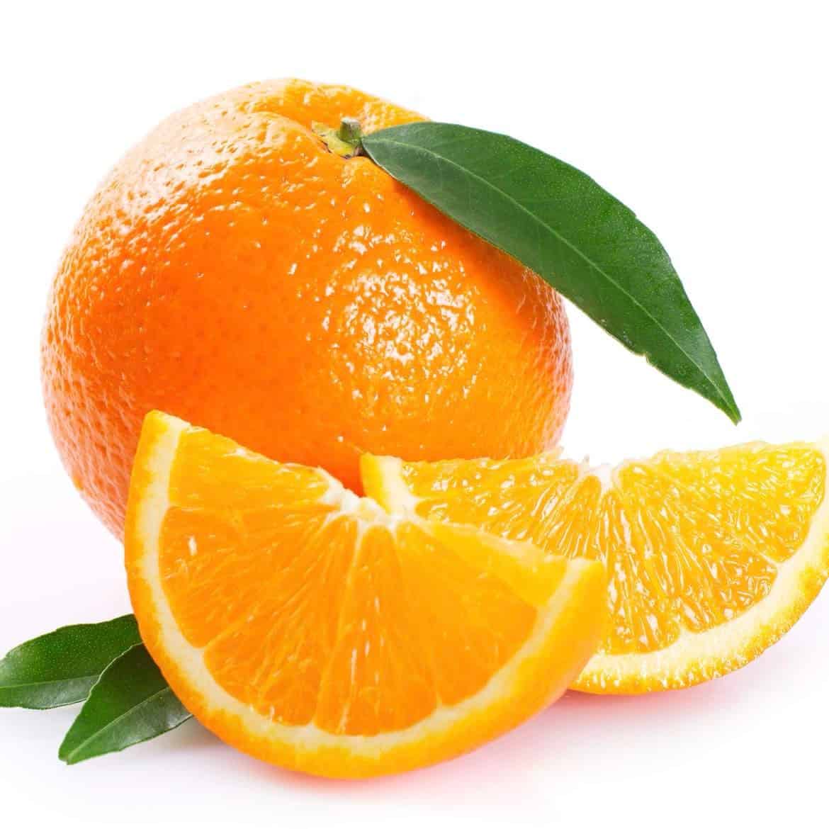 A fresh sweet orange with a couple of slices showing the tangy orange peel aroma, accompanied by green leaves.